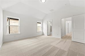 Vaulted ceilings, neutral carpeting, and multi-pane windows featuring crisp white trim