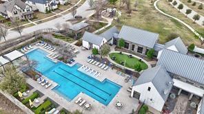 Aerial perspective of a multi-structure facility featuring a lap pool, stone-finish buildings with standing seam metal roofing, and a manicured central lawn