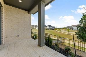 Covered patio featuring stone tile flooring, brick exterior walls, and a metal railing