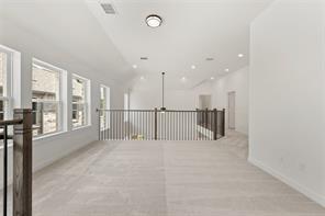 Vaulted ceiling featuring recessed lighting, carpeted flooring, and a dark metal balustrade with a wooden handrail