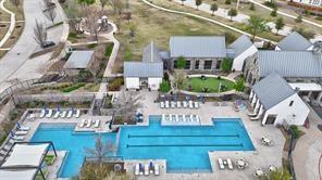 Multi-structure recreation complex featuring a lap pool with a designated shallow area, hardscaped stone pool deck, and pitched-roof buildings with metal roofing