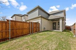 Rear exterior featuring light-toned brick masonry, wood-finish horizontal siding, a covered patio, and a fully enclosed wood privacy fence