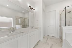 Dual-sink vanity with light-tone countertops, full-width wall mirror, glass-enclosed shower, and large-format tile flooring