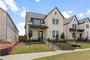 Two-story residence featuring a light-toned brick facade, gabled roofline, covered front entryway, and iron-style perimeter fencing