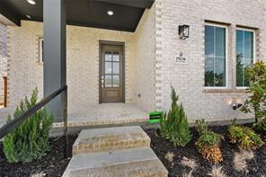 Light-colored brick exterior featuring a recessed entry with a dark-finished ceiling, a multi-pane wood-frame entry door, and stone steps leading to the threshold