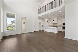 Vaulted ceilings, wood-finish flooring, island kitchen with pendant lighting, and a second-story mezzanine railing
