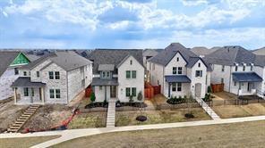 Residential streetscape featuring multi-story dwellings with stone and brick exteriors, pitched roofs, covered front porches, and concrete walkways
