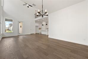 Open-concept interior featuring vaulted ceilings, wood-finish flooring, a multi-arm chandelier, and a recessed loft area
