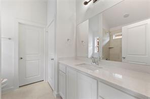 Bathroom vanity featuring white cabinetry, a light-toned solid surface countertop, an integrated rectangular sink, a chrome faucet, and a large frameless wall mirror