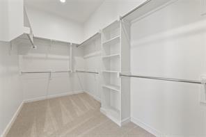 Walk-in closet featuring wall-to-wall carpeting, white shelving units, multi-tier metal rods, and recessed lighting