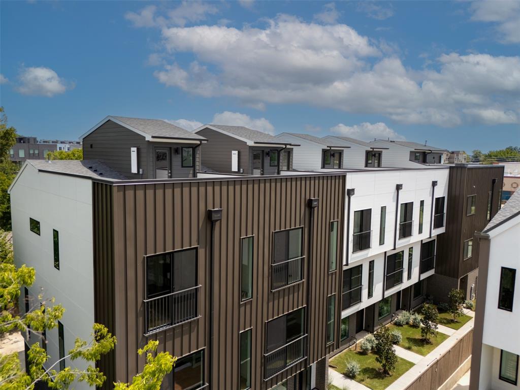 Multi-level structure featuring vertical metal siding, smooth paneling, private balconies with black metal railings, and roof deck access points