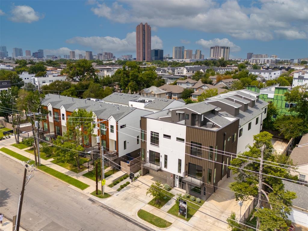 Multi-level townhome exterior featuring vertical metal siding, glass balcony railings, a concrete driveway, and a flat roofline