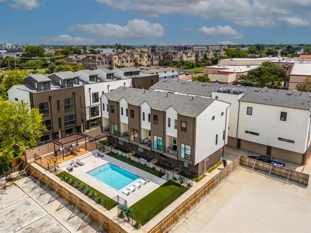 Multi-level townhome community featuring contemporary mixed-material siding, a shared swimming pool with integrated sun shelf, and a covered pergola area