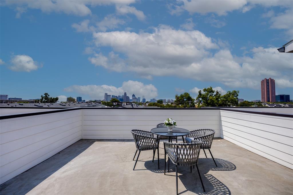 Rooftop terrace featuring white horizontal siding, a concrete floor, and an urban skyline backdrop