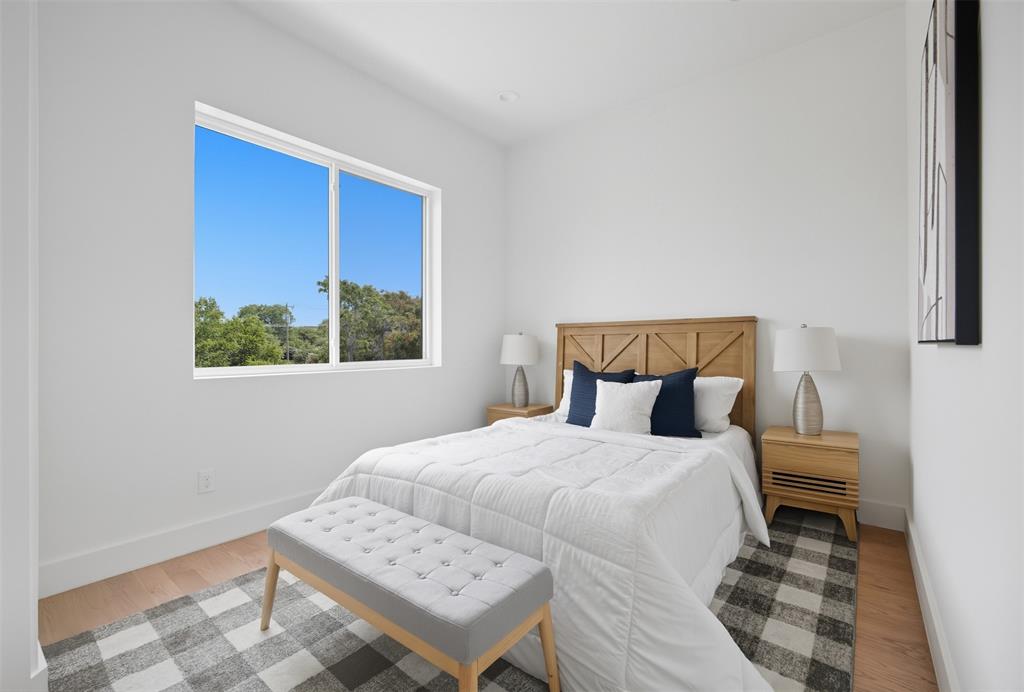 Neutral interior featuring wood-finish flooring, a large sliding window, and crisp white wall paint