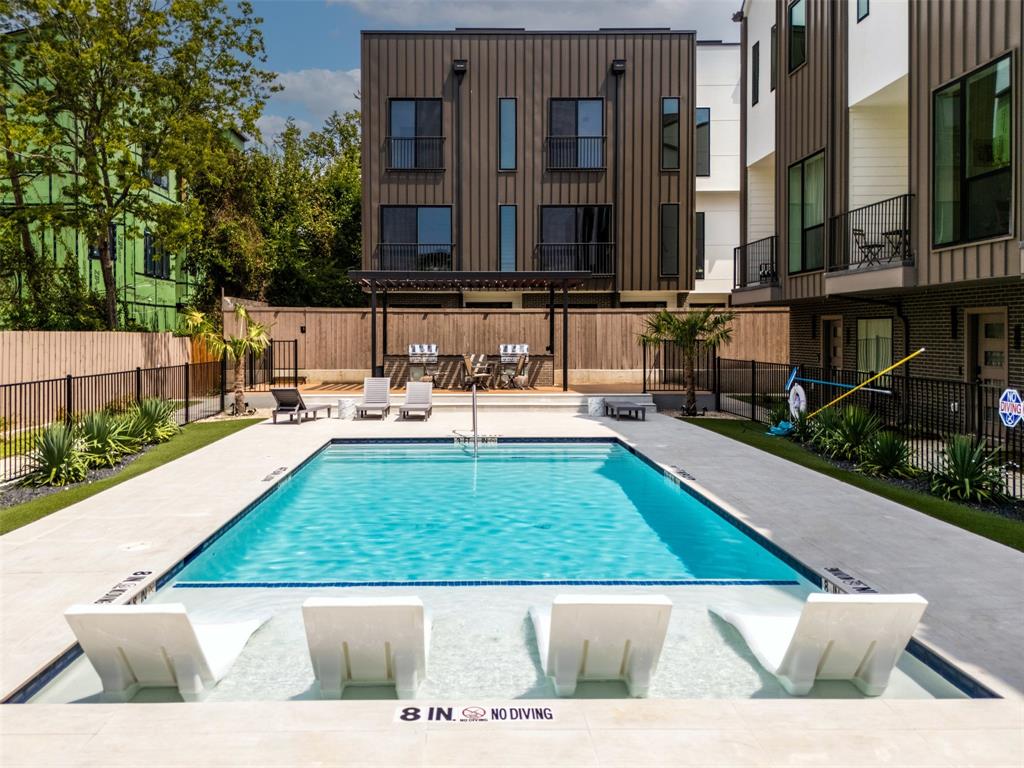 Swimming pool with built-in tanning ledge, concrete deck, metal pergola, and perimeter fencing