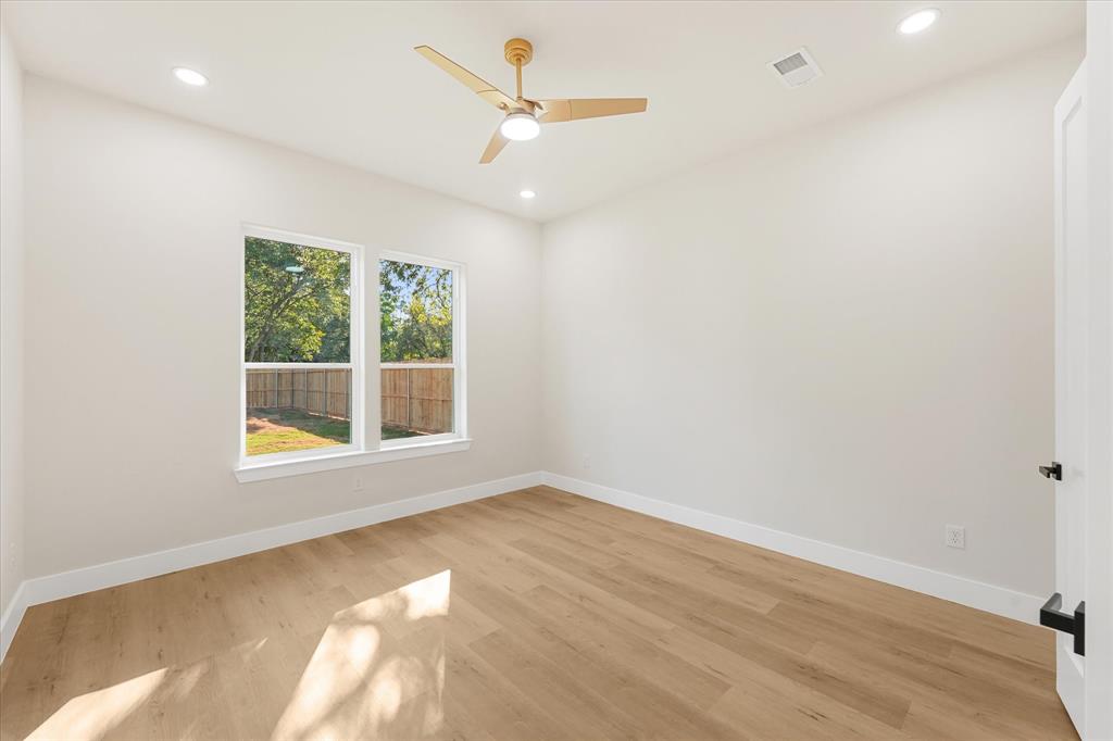 Room featuring wood-finish flooring, recessed lighting, a modern ceiling fan with integrated light, and dual pane windows