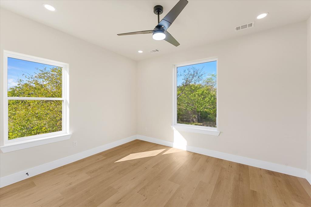 Neutral-toned interior featuring wood-finish flooring, dual-pane windows, recessed ceiling lighting, and a modern matte-finish ceiling fan with integrated light