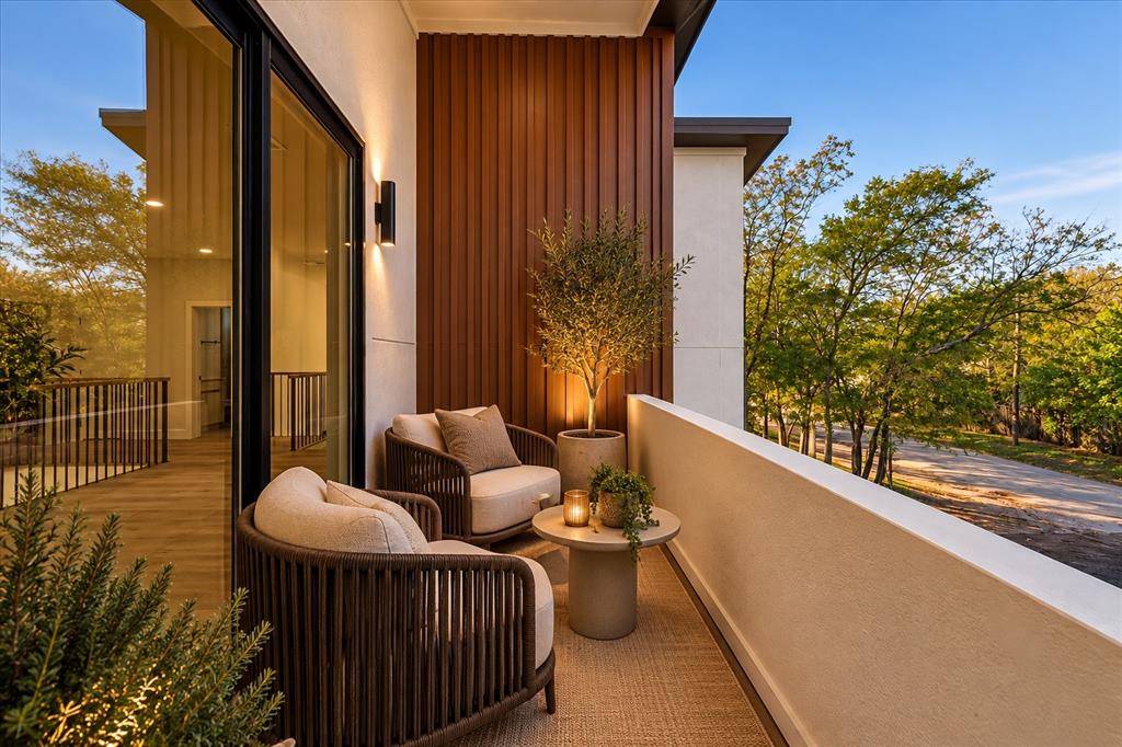 Covered balcony featuring vertical wood-slat siding, smooth stucco walls, and black-framed glass sliding doors with integrated wall-mounted lighting