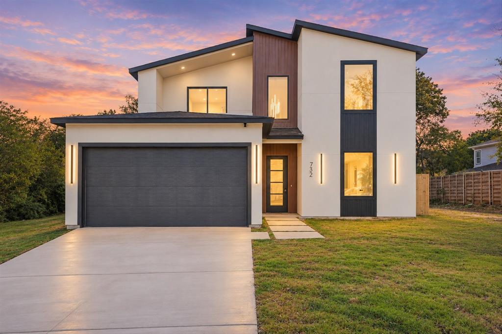 Contemporary two-story exterior featuring smooth stucco siding, vertical wood-finish accents, large rectangular windows, an attached two-car garage, and minimalist wall-mounted light fixtures