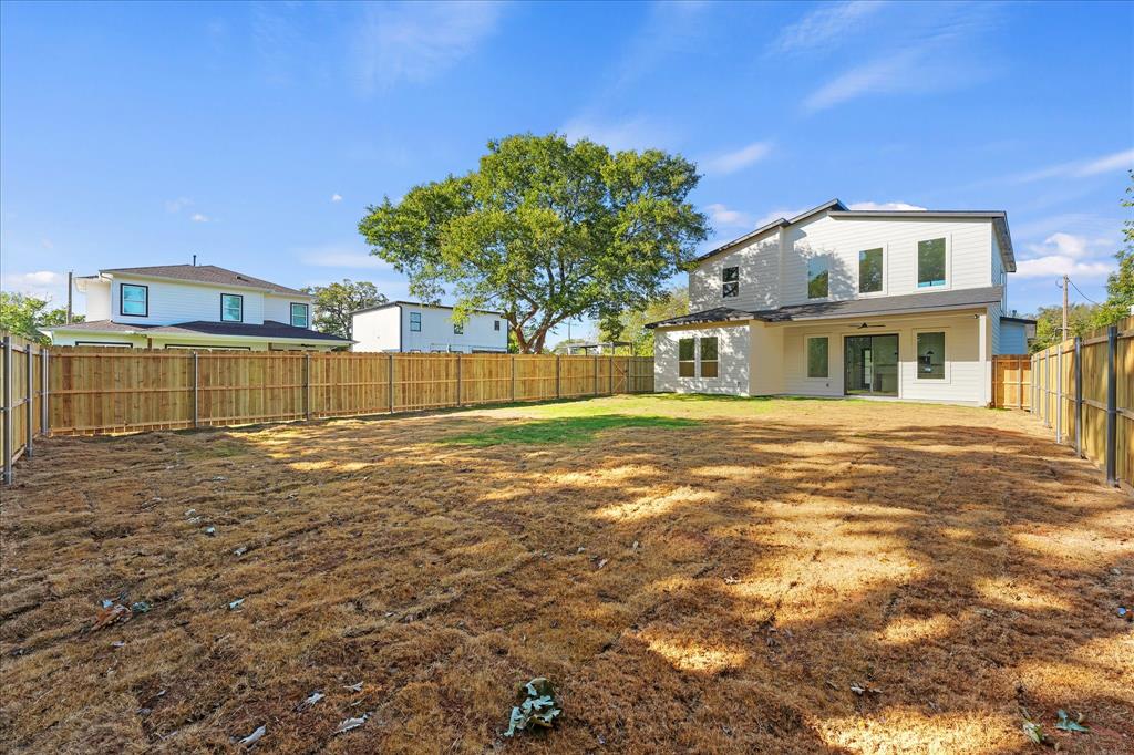 Expansive backyard featuring a wood privacy fence, multi-level exterior siding, and a covered rear patio