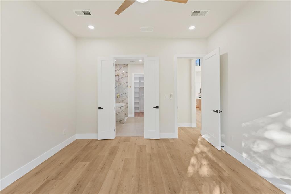 Room featuring wood-finish flooring, recessed lighting, a ceiling fan, and double interior doors with matte black hardware