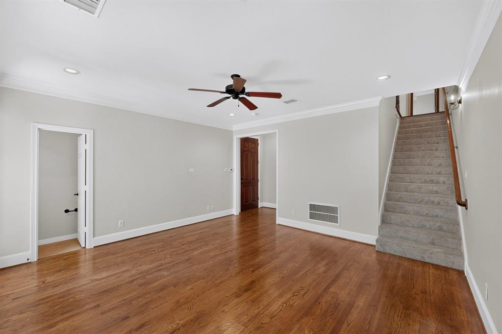 Interior space featuring wood-finish flooring, crown molding, recessed lighting, a ceiling fan, and carpeted staircase with a wooden handrail