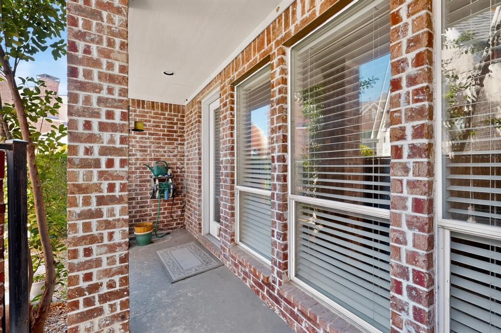 Covered exterior patio featuring red brick masonry, recessed lighting, and large windows with integrated blinds
