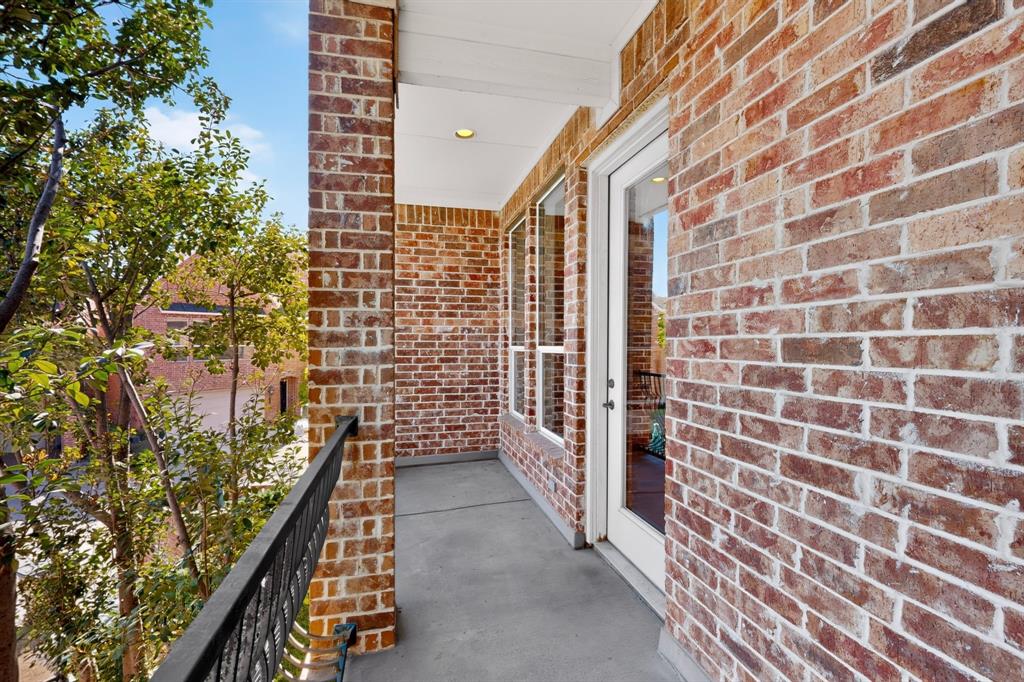 Covered balcony featuring exposed brick exterior walls, a concrete floor, recessed lighting, and a metal railing