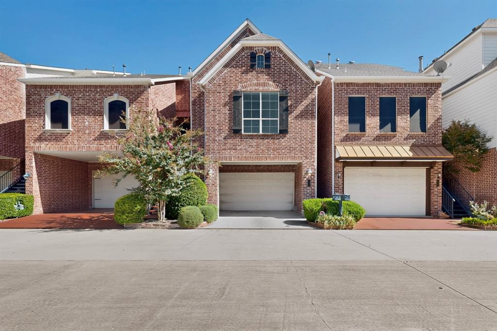 Multi-level brick exterior featuring arched window detailing, three-car garage capacity, decorative shutters, and metal roof accents