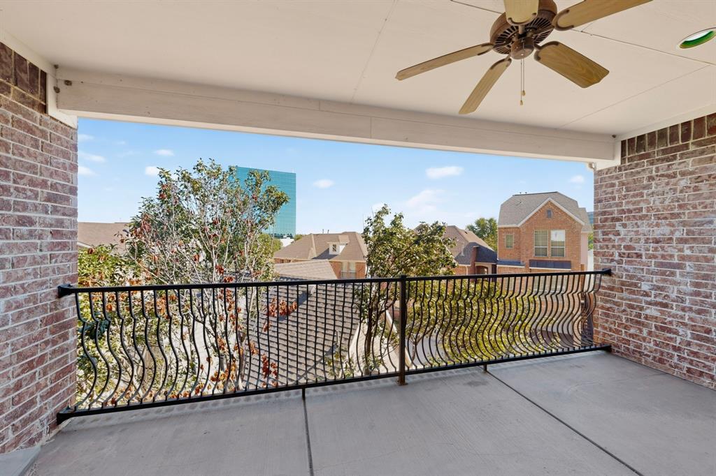 Covered balcony featuring brick masonry walls, wrought iron railing, and a ceiling-mounted fan