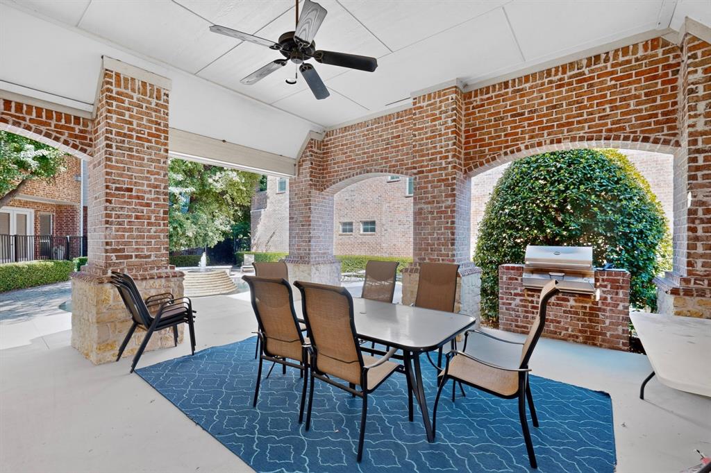 Covered patio featuring brick masonry columns with stone bases, integrated stainless steel grill, and ceiling fan