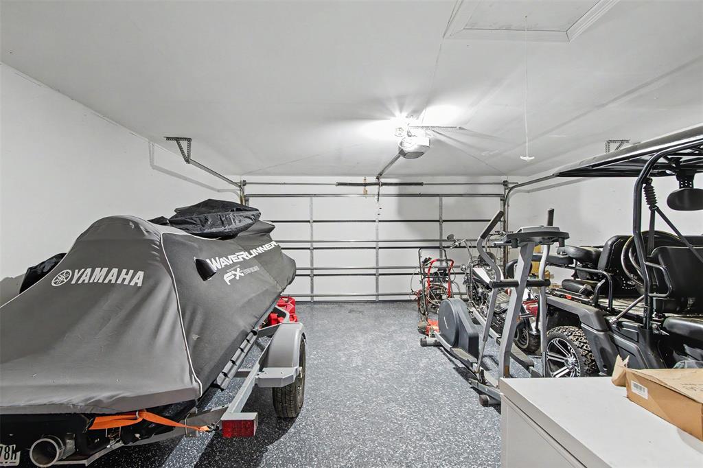 Attached garage featuring epoxy flooring, overhead storage access, and automated door opener