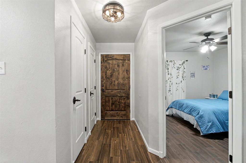 Wood-finish flooring throughout, rustic arched-top stained wood entry door, and industrial-style flush mount ceiling light fixture