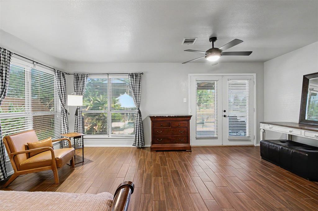 Wood-finish flooring, recessed lighting with integrated ceiling fan, and double glass-paneled doors providing exterior access