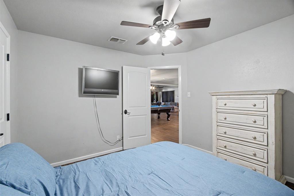 Room featuring neutral-toned walls, a multi-blade ceiling fan with integrated lighting, and a multi-panel interior door with dark hardware