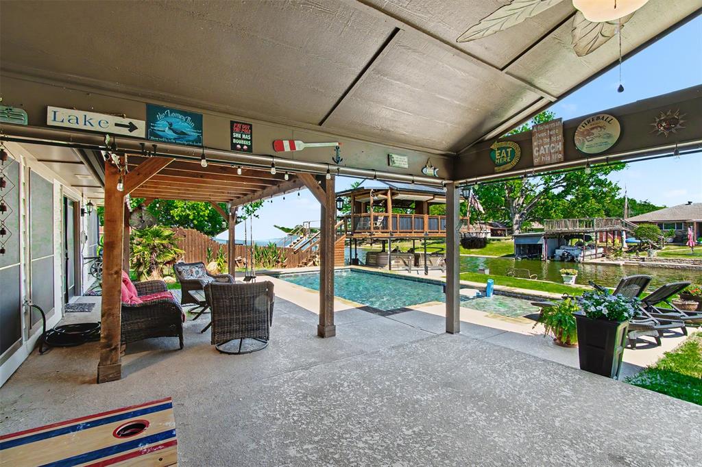 Covered patio with wood-post support beams, concrete flooring, and an inground swimming pool situated on the water's edge