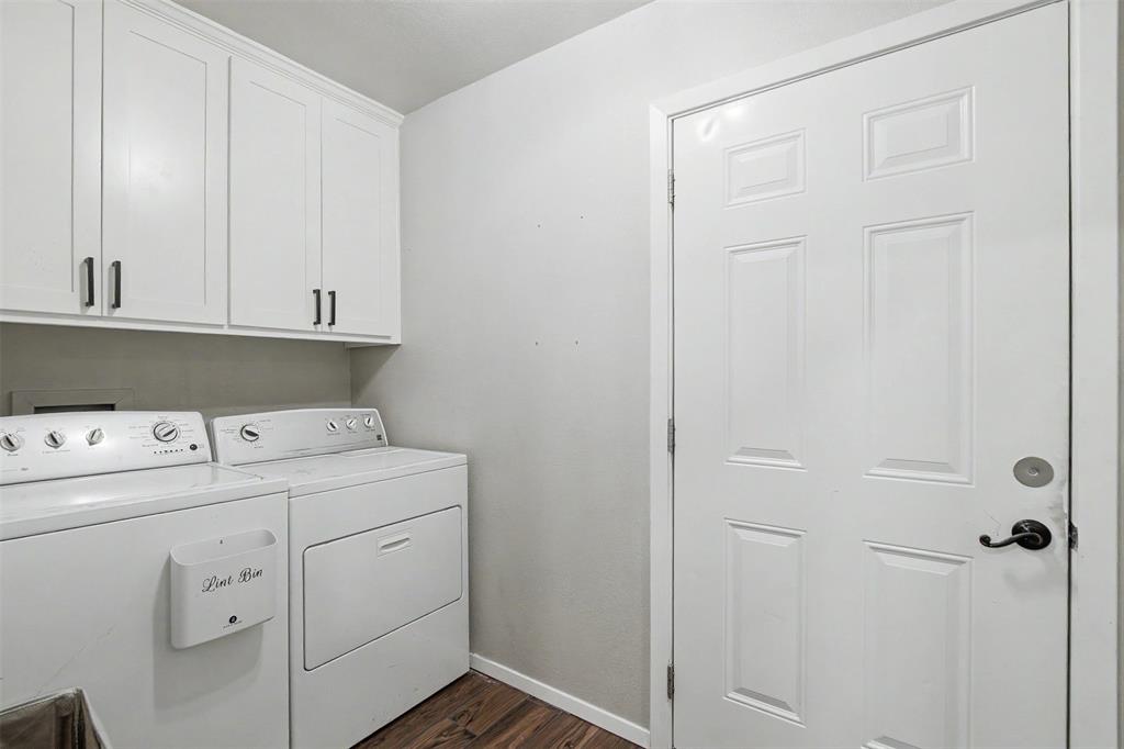 Laundry area featuring white Shaker-style wall cabinetry with matte black hardware, wood-finish flooring, and a six-panel door