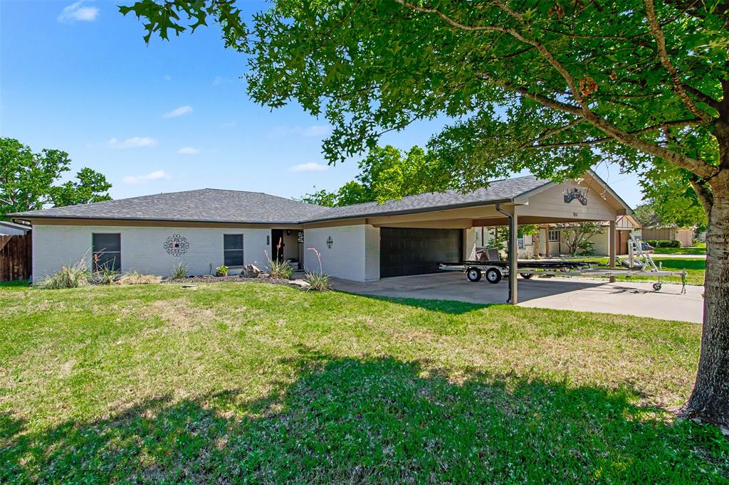 Single-story exterior featuring painted brick masonry, a gabled roofline, and an attached covered carport with a concrete drive Single-story exterior featuring painted brick masonry, a gabled roofline, and an attached covered carport with a concrete drive