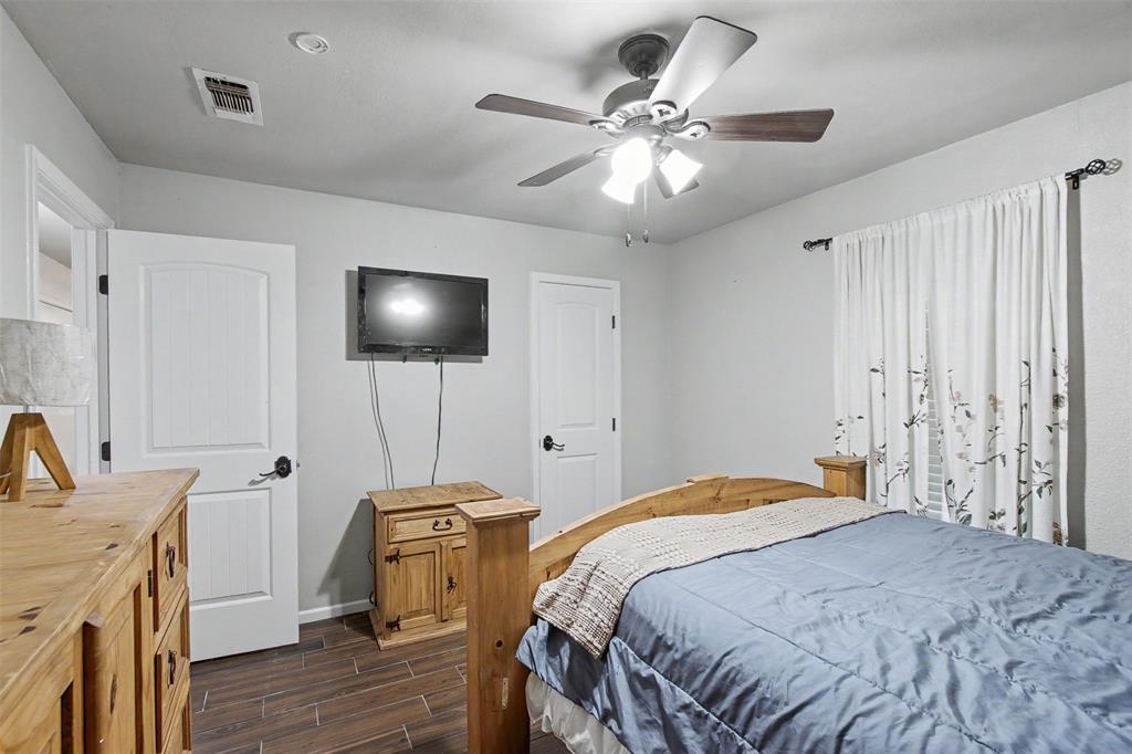 Room featuring wood-finish tile flooring, ceiling fan with integrated lighting, and two-panel interior doors with matte black hardware