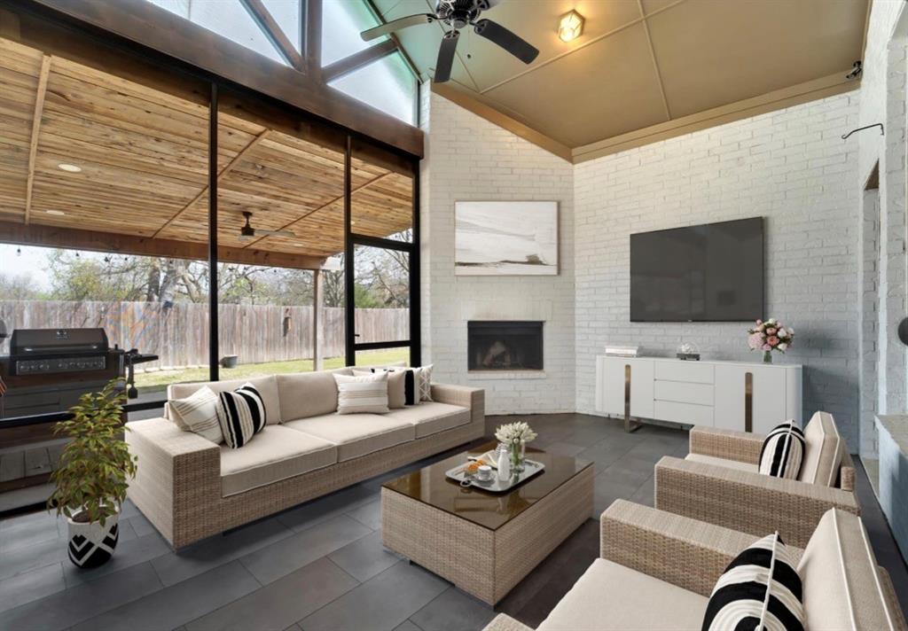 Screened porch featuring a vaulted ceiling with wood-paneled accents, white painted brick walls, tile flooring, and a corner fireplace