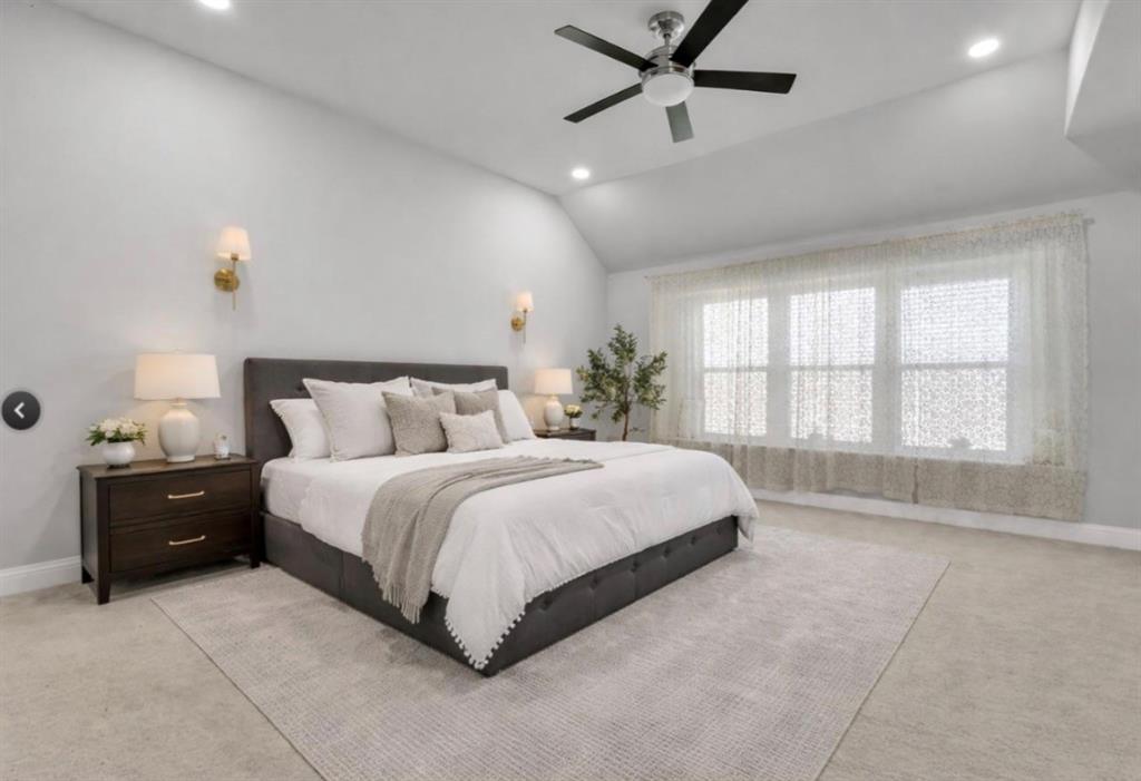 Vaulted ceilings, neutral wall-to-wall carpeting, recessed lighting, multi-blade ceiling fan, and dual wall-mounted light fixtures
