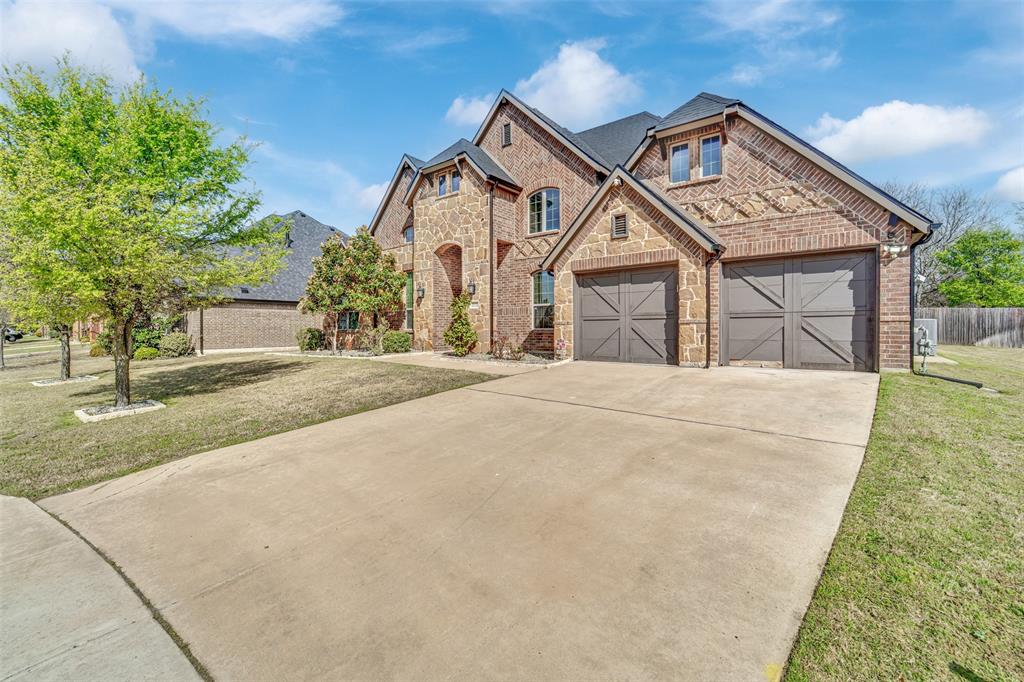 Brick exterior featuring multi-gabled rooflines, decorative masonry detailing, and attached two-car garage with cross-buck carriage doors