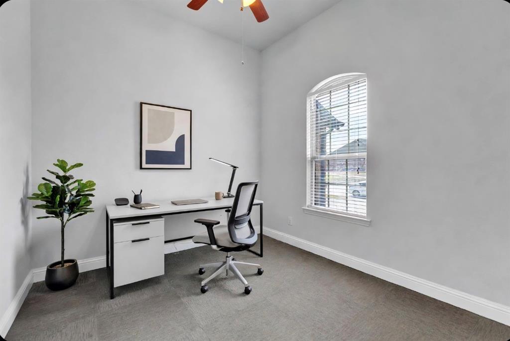 Room with neutral wall color, carpeted flooring, arched window, and ceiling fan