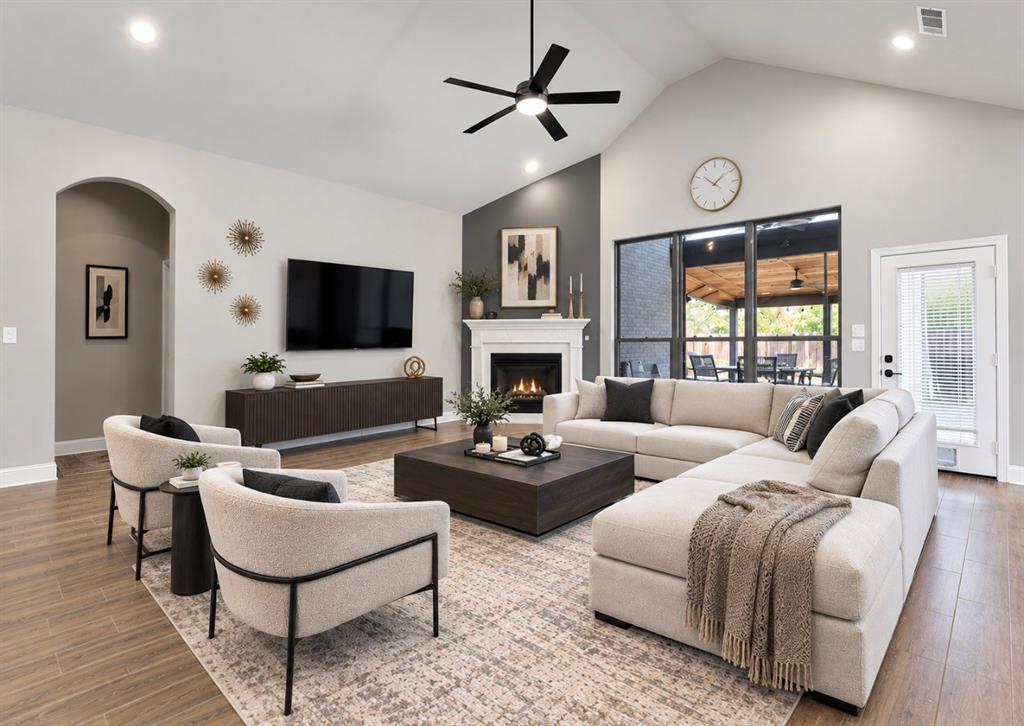 Vaulted ceilings, fireplace with a white mantel, wood-finish flooring, recessed lighting, and a modern ceiling fan