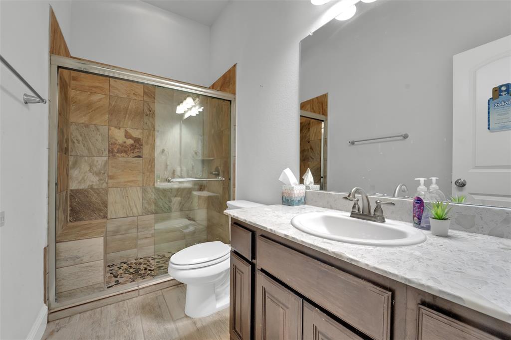 Bathroom featuring a vanity with a light-toned stone countertop, an integrated oval sink, and dark wood-finish cabinetry