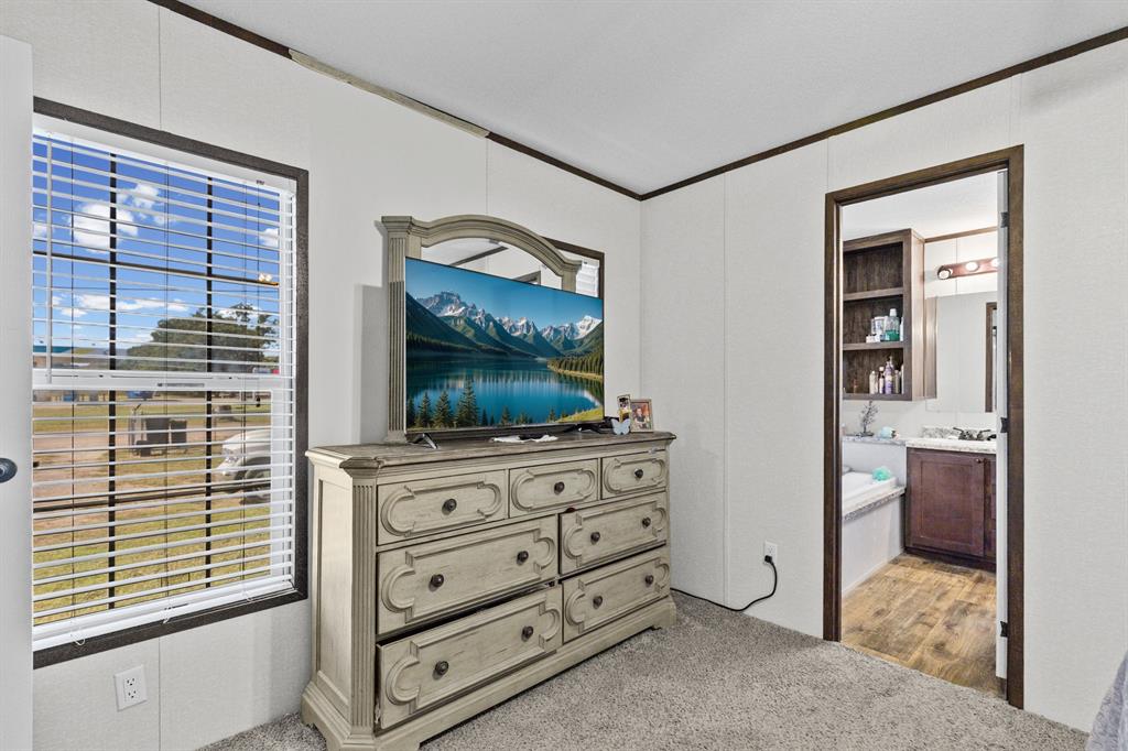 Room featuring neutral wall paneling, dark trim, carpeted flooring, and a window with blinds