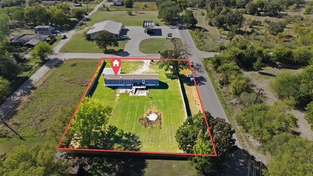 Aerial perspective of a property featuring an expansive fenced-in backyard, a ground-level patio, mature trees, and a detached structure