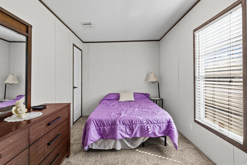 Neutral interior room featuring wall-to-wall carpeting, high-contrast dark wood-finish door and window trim, and a window fitted with horizontal blinds