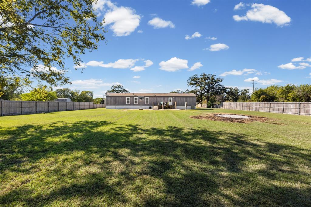 Expansive backyard featuring a level lawn, full-perimeter wood fencing, and mature trees